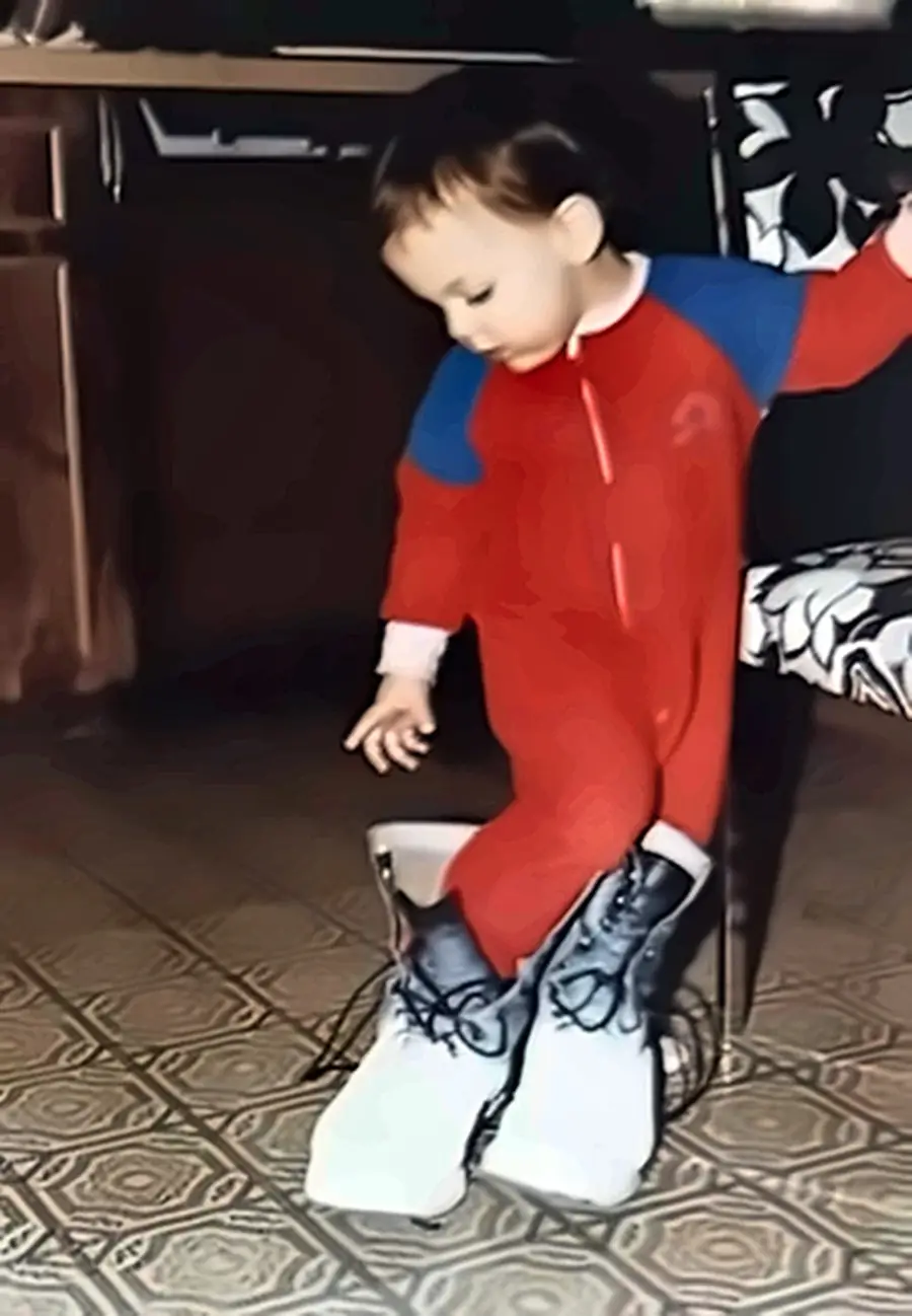 Michael Venturini as a toddler standing in his father's work boots